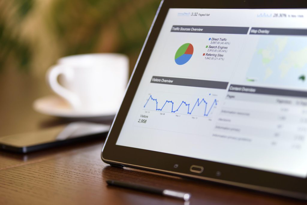 A tablet showing analytics charts on a desk next to a notebook